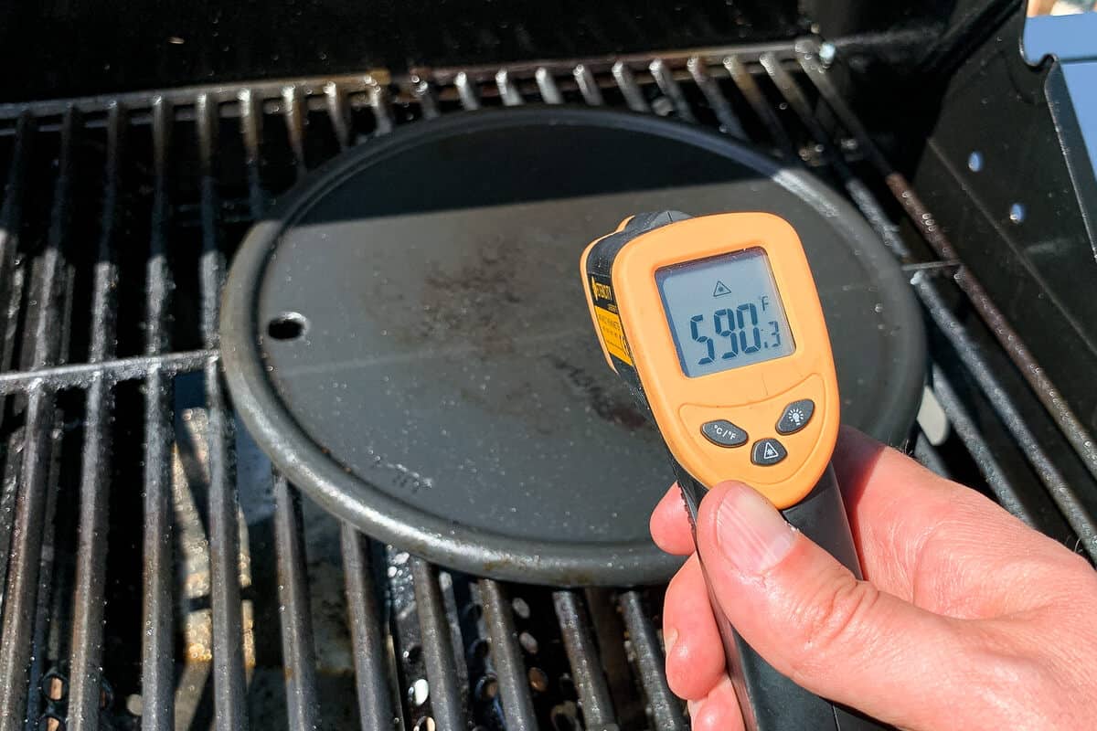 an infrared thermometer aimed at cast iron pan to show the temperature of 590 degrees