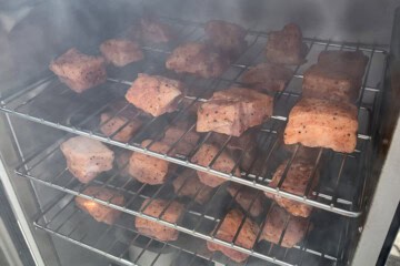 pork belly chunks smoking inside an electric smoker
