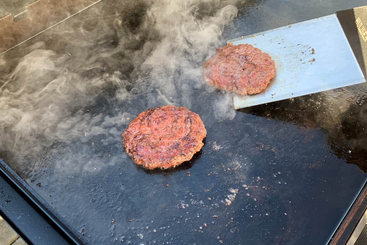 smash burgers on the surface of a blackstone griddle