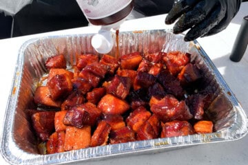 BBQ sauce being drizzled over cubes of pork belly