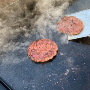 smash burgers on the surface of a blackstone griddle