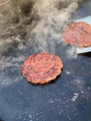 smash burgers on the surface of a blackstone griddle