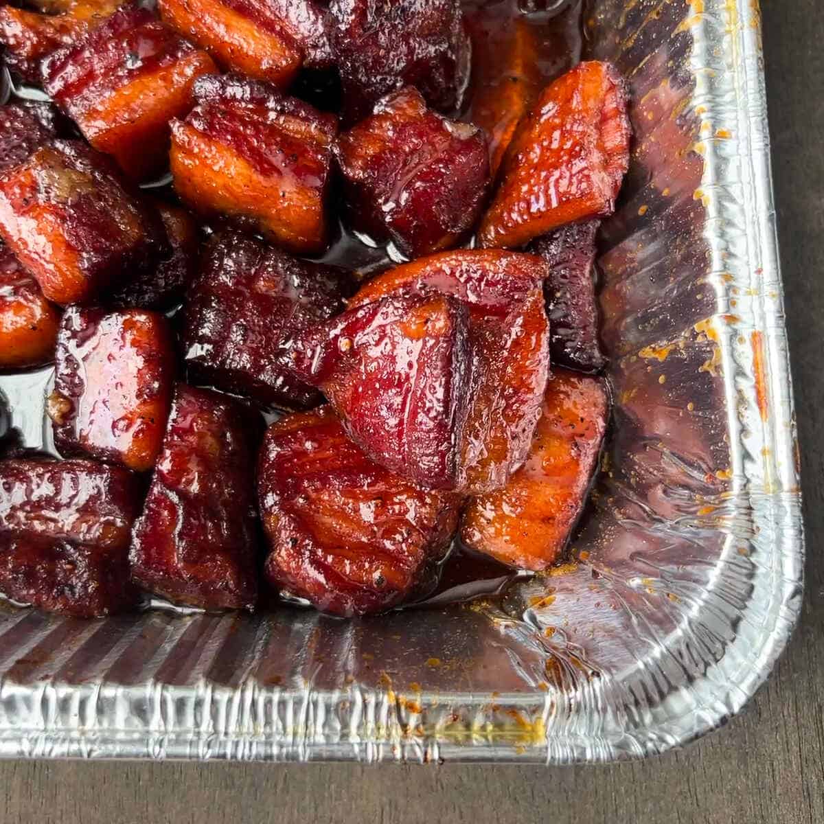 pork belly burnt ends in an aluminum foil pan