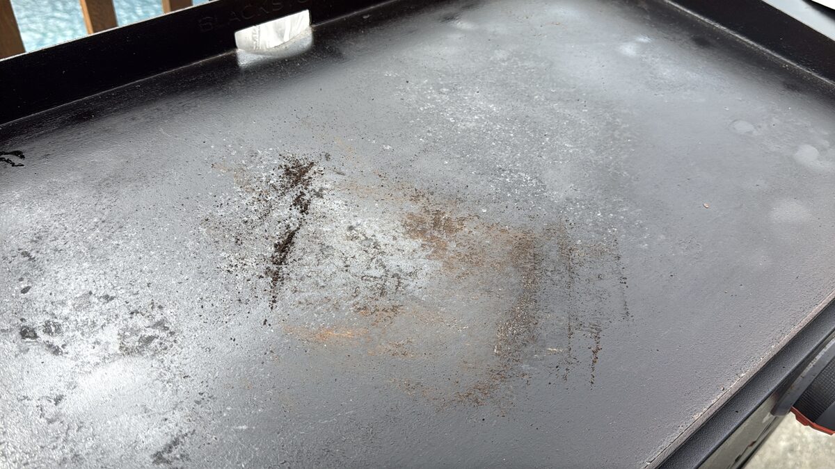 the surface of a Blackstone griddle looking like it is flaking with built up seasoning