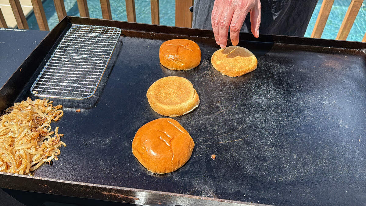 hamburger buns face down on a Blackstone griddle toasting