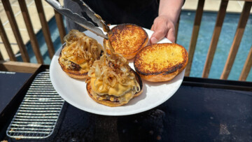 grilled onions being added to the top of smash burgers