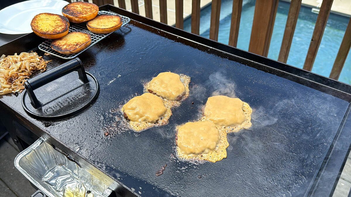 4 burgers on a Blackstone griddle with melted cheese on top