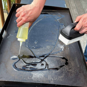 a Blackstone griddle with oil being poured on it