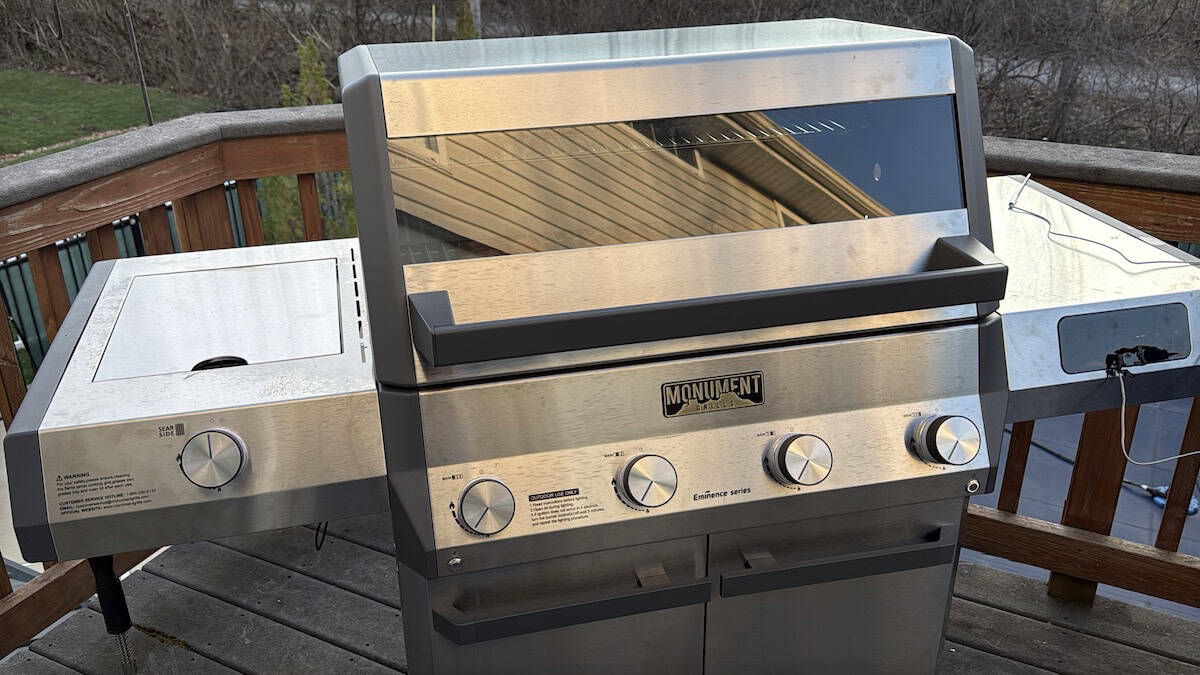 Outdoor stainless steel gas grill on wooden deck for barbecues.
