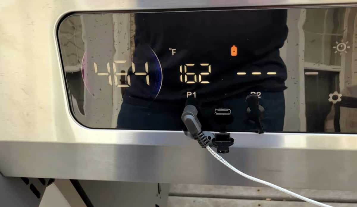 Smart thermostat with digital display showing indoor temperature and Wi-Fi status.