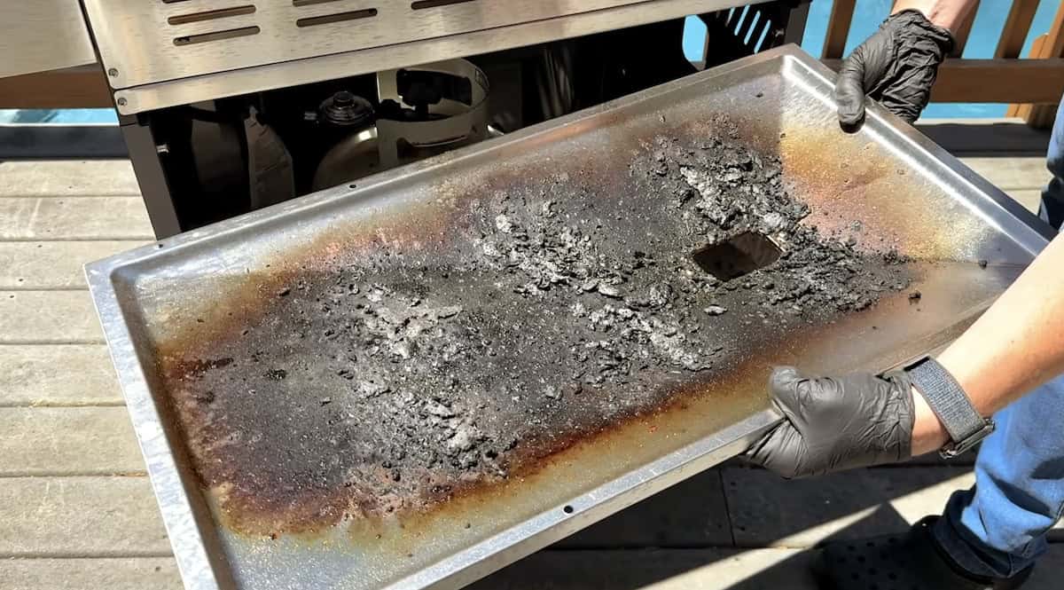 Charcoal grill with ash and residue after cleaning process.